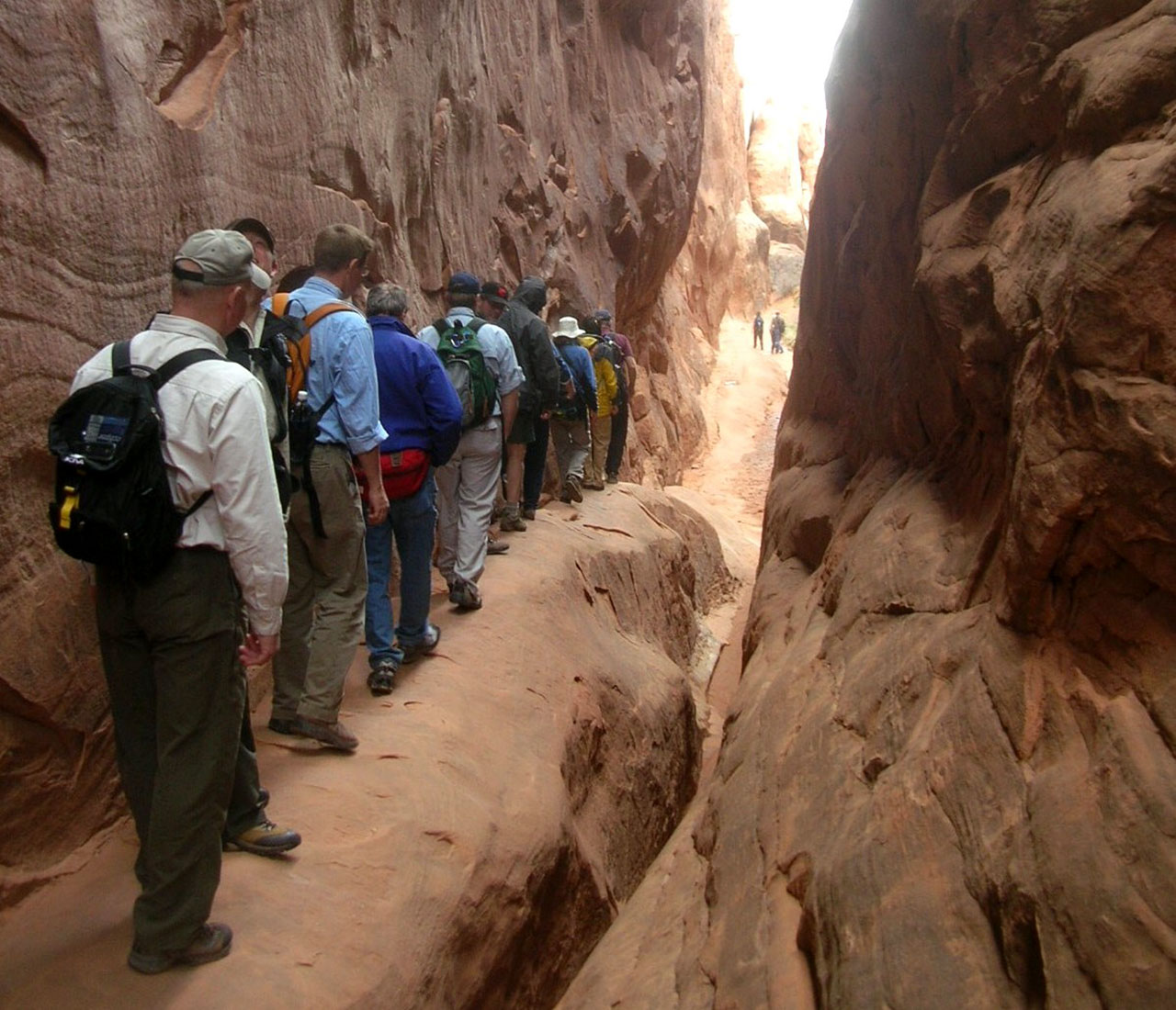 People walking along a thin desert shelf trail