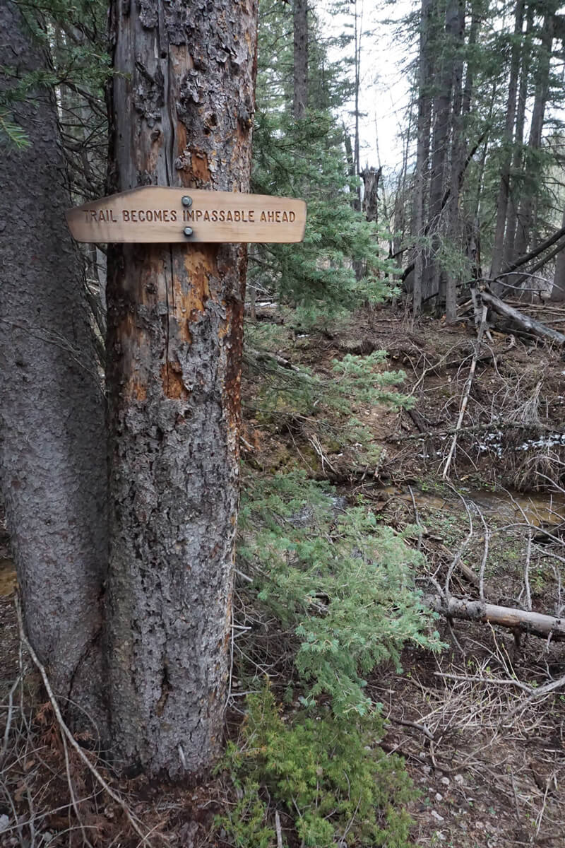 Sign on tree noting the trail ahead becomes impassable