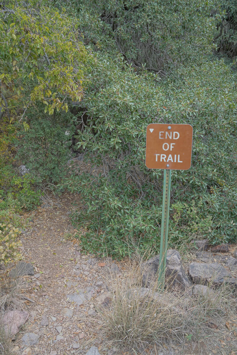 A metal sign at the end of a trail