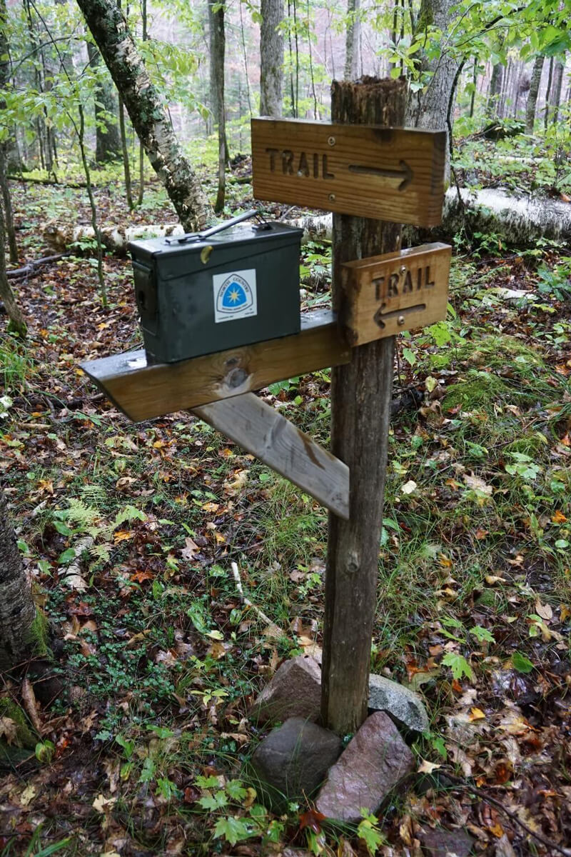 Wood sign post with metal box held in place by rocks