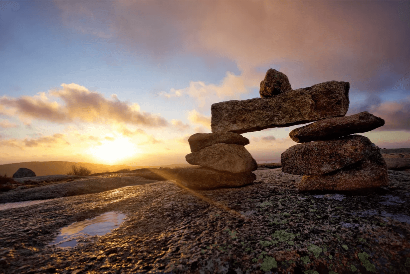 A rock cairn with the sunset behind it