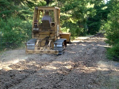 bulldozer breaking up the soil on a old road