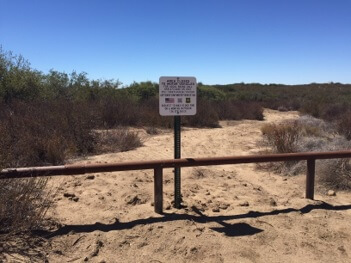 sign with alternative sites for motor-based recreation with a metal fence in a desert environment
